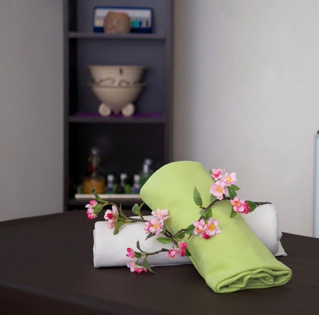 Massageliege, darauf Deko-Tücher und ein Blütenzweig